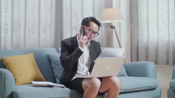 Asian Businessman In Jacket And Shorts Holding A Paper And Talking On Phone While Working