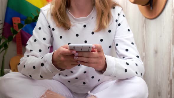 Young Millennial Hippie Woman Sitting on Balcony Using Mobile Phone