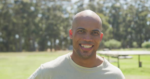 Portrait of african american male soldier with shaved head smiling in sun at obstacle course