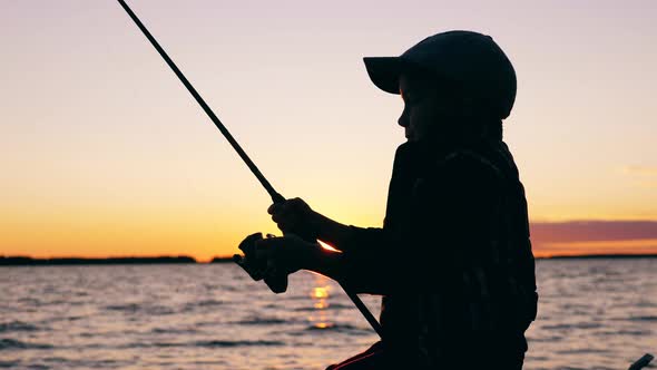 A Child Is Using a Fishing Pole for Fishing at Sunset