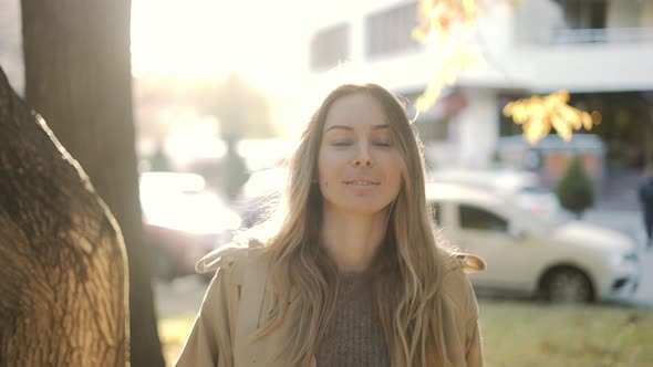 Woman in Nature Near Coniferous Trees and Bright Sunlight on the Background