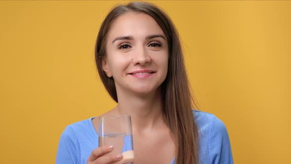 Closeup Portrait of Happy Young Woman Drinking Clean Pure Water Glass Posing Isolated on Orange
