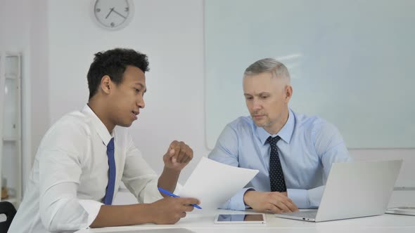 African Businessman Discussing Project Documents with Senior Grey Hair Businessman