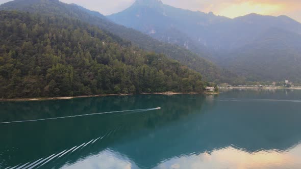 Aerial view on the water of Ledro lake, Trentino, Italy. Drone follows a little boat in the lake. 4k