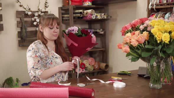 a Young Woman Cuts Off a Piece of Ribbon From the Bouquet She Made