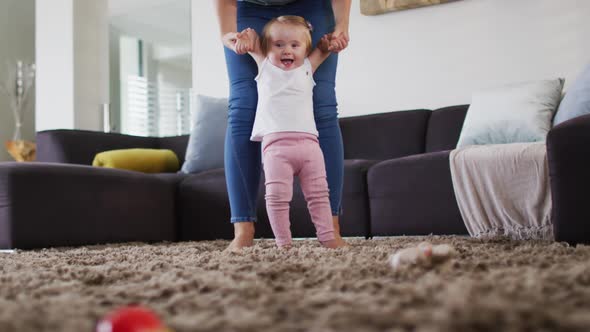 Mid section of caucasian mother teaching her baby to walk at home