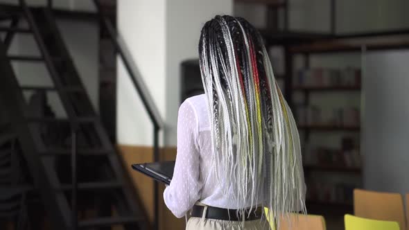 Rare View of Walking Woman with Long Black and White Dreadlocks Looking on Tablet in Her Hands