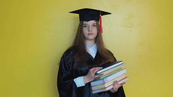 Caucasian Girl Student Holds Many Books While Staying in Front of Camera with Graduating Diploma in