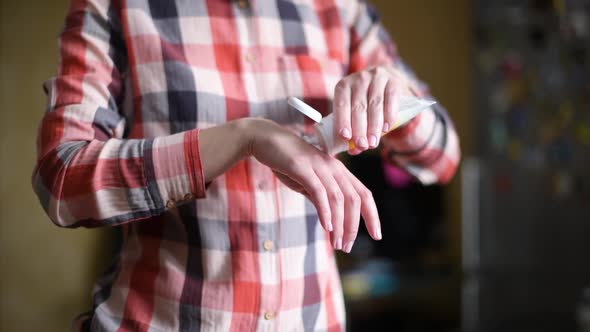 girl squeezes a small amount of hand cream and rubs it on the hands