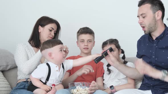 A Large Family with Three Children Spends the Weekend at Home in Front of the TV and Eating Popcorn