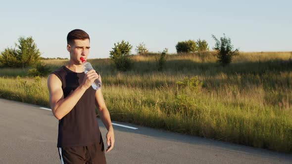 Young Jogger Walking to Sun Shining on Road at Nature and Drinking Water