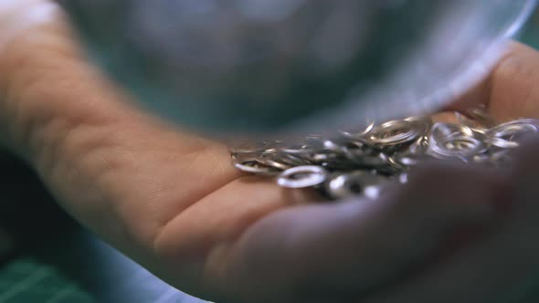 Skilled Tailor Fills Hand with Various Silver Eyelet Parts