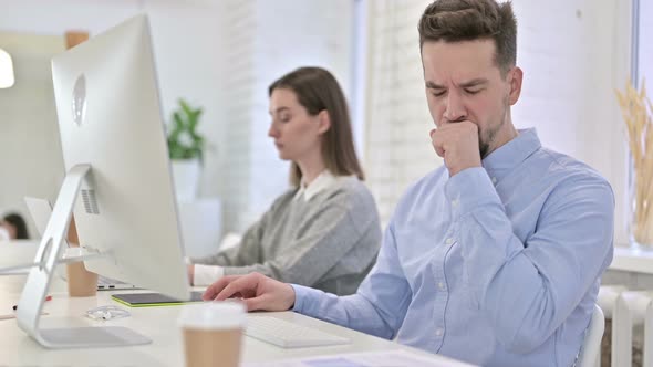 Creative Man Working on Desktop and Coughing in Office