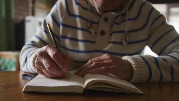 Senior man writing in a book at home