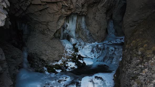 The Stream of the Mountain River in a Narrow Gorge Covered with Ice