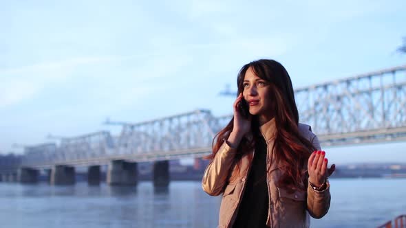 Portrait of the Happy Young Woman Talking on the Phone on Waterfront Near River