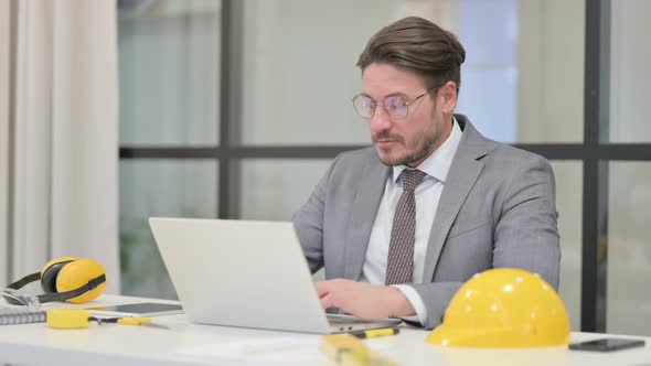 Middle Aged Engineer Working on Laptop in Office