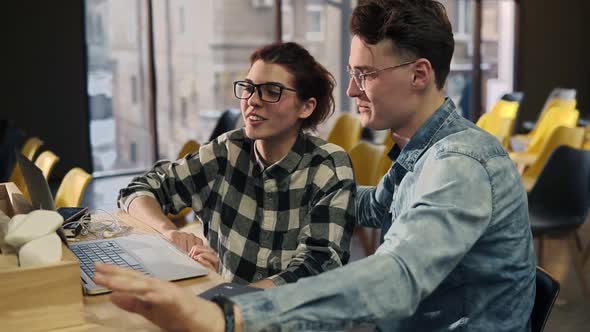 A Couple of Two Young People Wearing Glasses Sitting Next to Each Other Talking with Someone Through