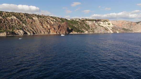 Video From a Drone a Bay with a High Rocky Seashore and Drifting Yachts on the Water