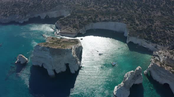 Aerial Wide Establishing Shot of Tropical Bay in Greece with White Rocks and Boats in the Ocean