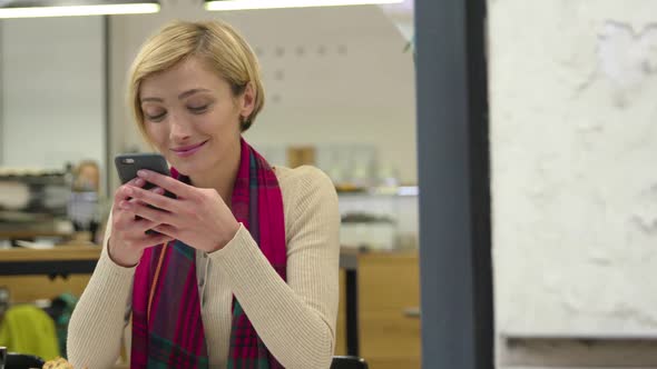 Technology. Smiling woman using mobile phone in cafe indoors