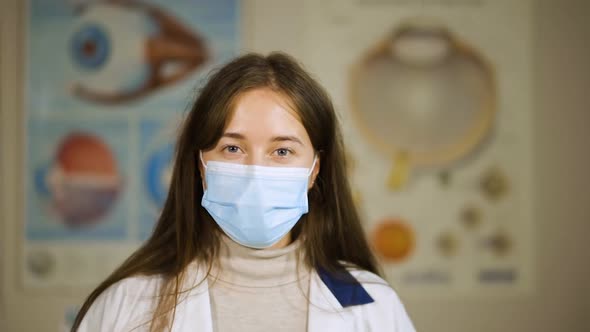 Happy Young Doctor in Medical Face Mask Looks at You