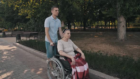 Man Walking with Old Woman on a Wheelchair