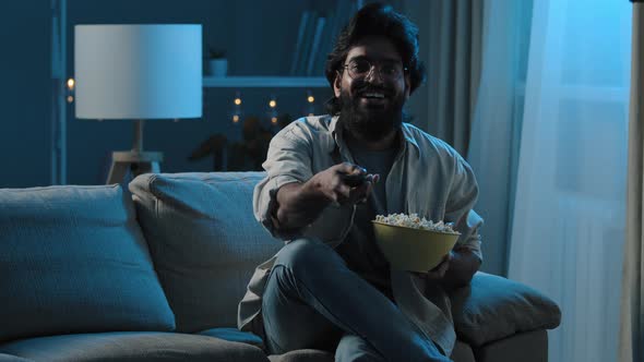 Arab Adult Bearded Man in Glasses Indian Male Bachelor After Work Sits on Sofa in Dark Living Room