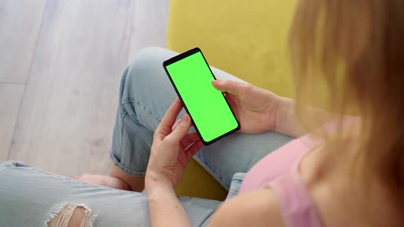 Rear View of Phone with Green Screen Chroma Key in Hands of Blonde in Pink Top