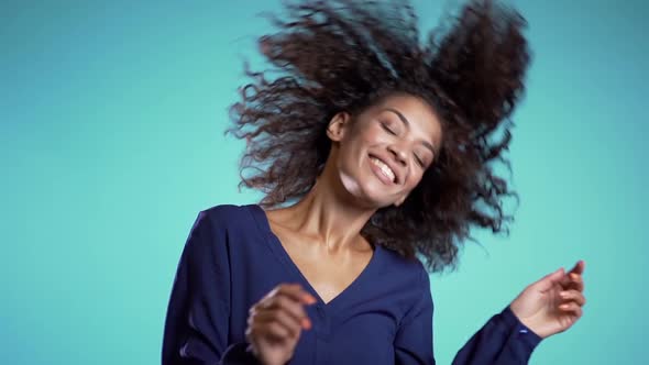 Beautiful african american woman with afro hair having fun smiling and dancing in studio 