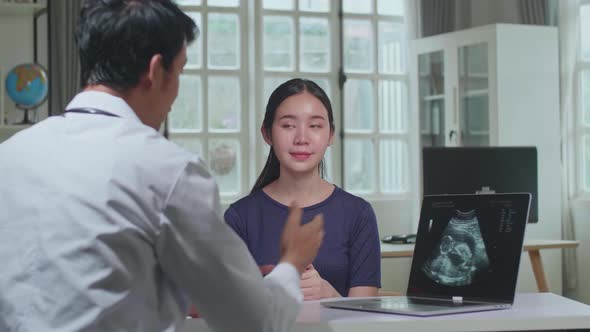 Asian Man Doctor Is Talking With Young Female Patient During Consultation