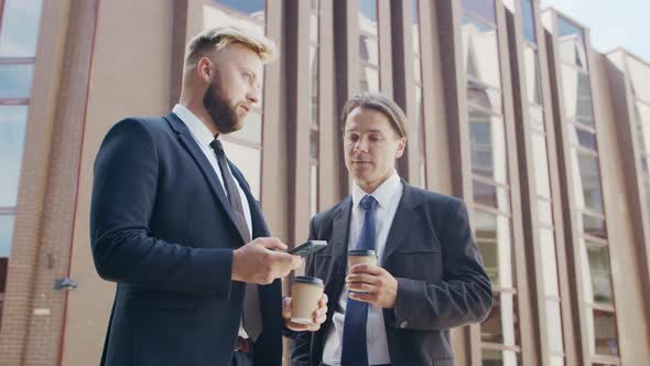 Confident businessman and his colleague in front of modern office building.