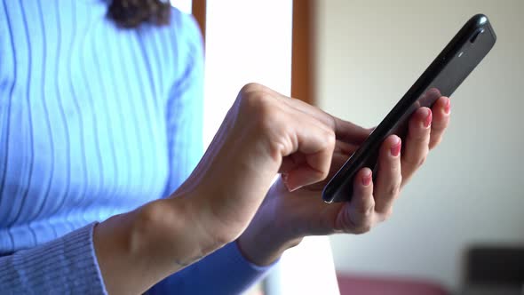 Woman's hand using smartphone and finger wiping on display