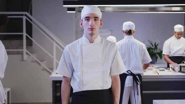 Caucasian male cook working in a restaurant kitchen looking at camera and smiling