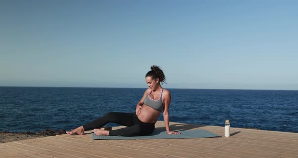 Young pregnant woman doing yoga outdoor - Sport exercises and maternity concept