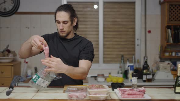 Young Caucasian Man Enjoying the Smell of Raw Meat After Opening Tray with Knife in Traditional