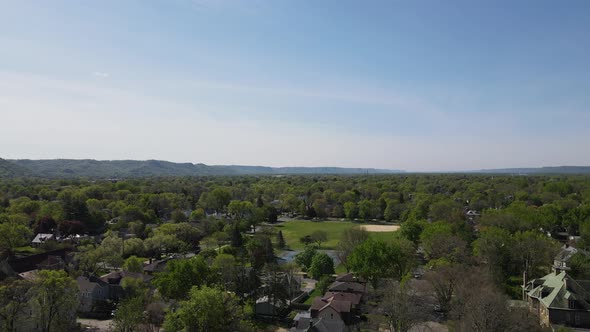 Drone view over midwest city with bluffs in the background and tree lined streets in community.