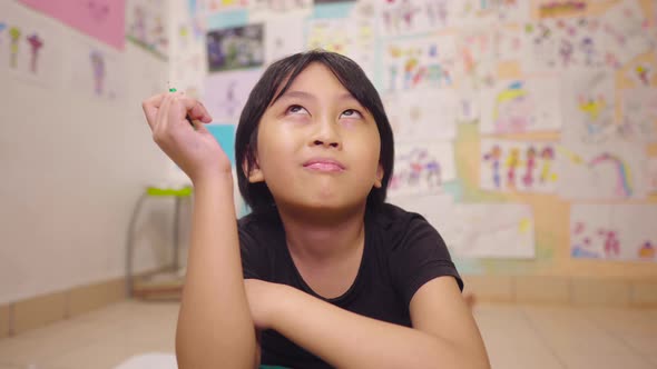 Young Asian boy in Art Room taking a break and thinking what drawing or painting he will create next