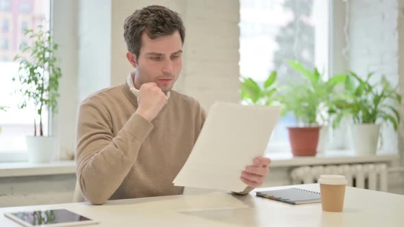Man Upset While Reading Documents in Office