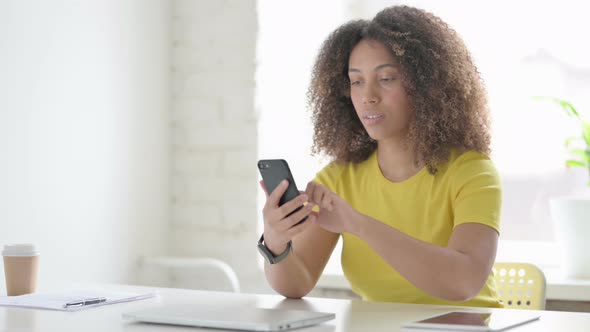 African Woman Browsing Internet on Smartphone at Work