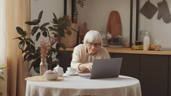 Elderly Woman Typing on Laptop at Home
