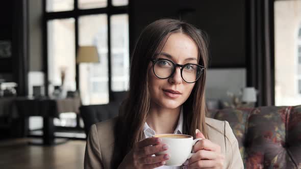 Charming Pensive Business Woman Holding Coffee in Hotel Lounge Thinking