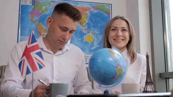 A Couple in a Travel Agency Against the Background of a Wall with a World Map