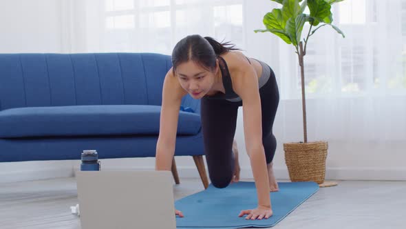 Athlete Asian young woman doing Mountain Climber online exercise class at home.Healthy female in spo