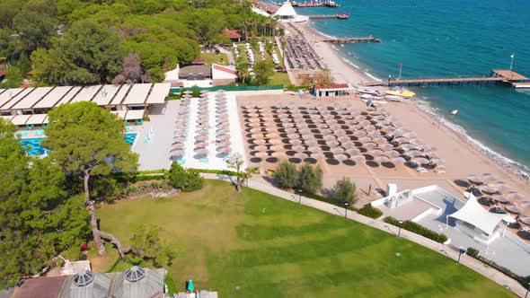 Flight Over the Beach with Umbrellas Towards the Pool in a Luxury Hotel