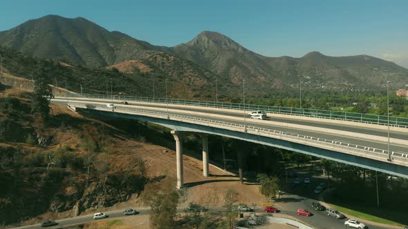 Aerial reveal of Highway Overpass with mountains on the background on a sunny day in Santiago de Chi