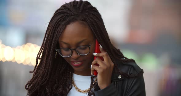 Bokeh Medium Shot of Young Afro Woman Outdoors on Summer Day Speaking on Cellphone