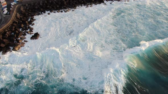 Aerial shot of strong ocean waves crashing on the volcanic coast