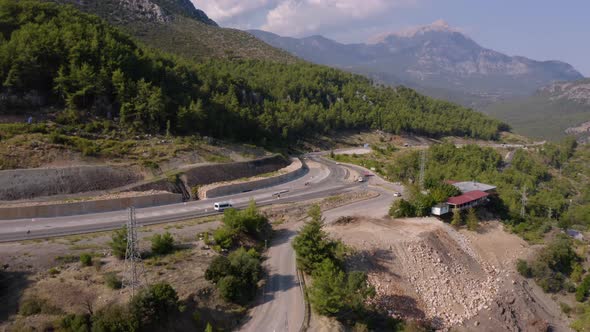 Aerial View of Road with Driving Cars Through Forested Mountains