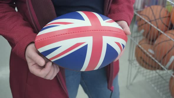 Woman in a Shop Buys Rugby and American Football Ball with Print of British Flag